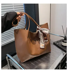 Detail of caramel brown tote bag with contrast stitching and decorative silk scarf accessory