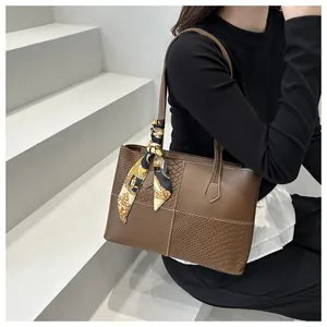 Detail of snake skin patchwork on large brown tote bag with decorative silk scarf handle