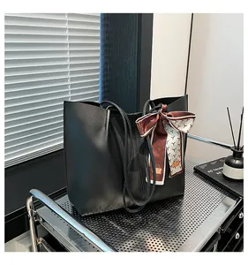 Detailed view of black tote bag with textured faux leather and decorative silk scarf detail