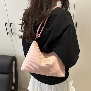 Bolso de hombro rosa claro plisado con rayas llevado por modelo en un interior