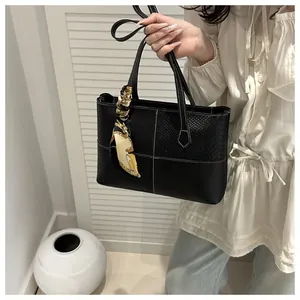 Detail of black tote bag with snake skin texture, white stitching and silk scarf wrap
