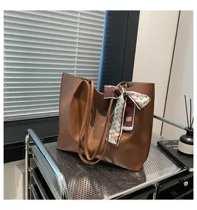 Close-up of brown faux leather tote bag with geometric print silk scarf detail and straps