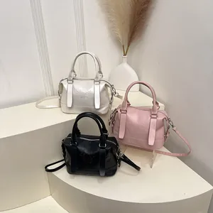 Tre borse a bauletto in pelle bianca, rosa e nera su un supporto minimalista