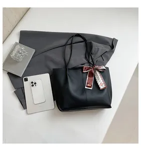 Detail of black leather tote bag showing large capacity for tablet and phone with silk scarf