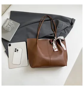 Detailed view of a brown tote bag with decorative silk scarf on a business desktop
