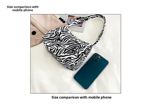 Detailed comparison of zebra print shoulder bag size with a smartphone on white background