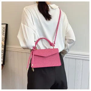 Détail d'un sac à main tissé rose avec texture à carreaux et poignée à nœud élégante