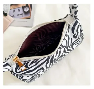 Detail of a zebra print tote bag featuring a white zipper and a polished gold metal puller