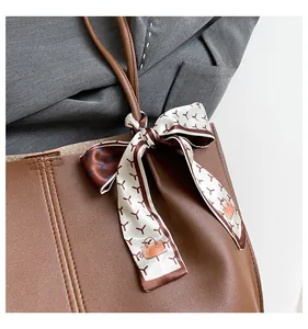 Detail of a brown tote bag with decorative patterned silk scarf and slim shoulder strap