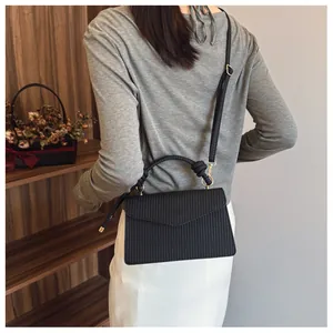 Vue arrière d'un sac carré noir texturé minimaliste porté en sac à bandoulière chic
