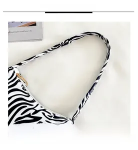 Detailed close-up of zebra print canvas shoulder bag with gold metal zipper closure