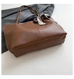 Close-up of caramel brown tote bag with premium leather texture and patterned silk scarf