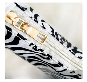 Detail shot of the golden metal zipper and zebra stripe pattern on the shoulder bag