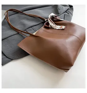 Detail of dark brown tote bag with decorative printed silk scarf and curved stitching