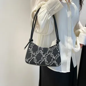 Black quilted denim shoulder bag with white diamond stitching and knotted straps