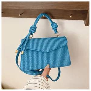 Détail du sac à main trapèze tressé bleu avec poignée à nœud et détails dorés