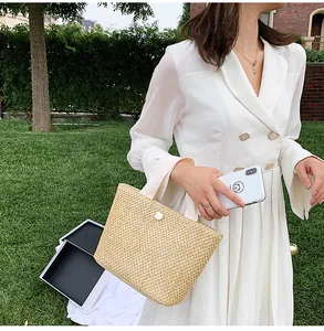 Detail of straw woven handbag featuring a white ball button closure and sturdy fabric handles
