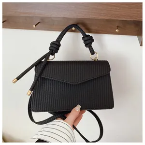 Détail d'un sac noir à texture tissée avec poignée nouée et cordons décoratifs à bout métallique