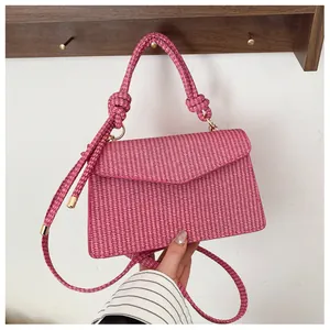 Détail d'un sac carré tissé rose avec une poignée en corde tressée et un nœud décoratif