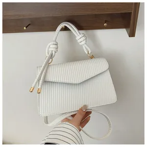 Détail du sac à main en cuir tressé blanc avec nœud décoratif et finitions dorées chic