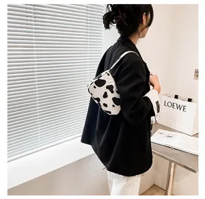 Detailed back view of model wearing cow print crescent shoulder bag with black blazer