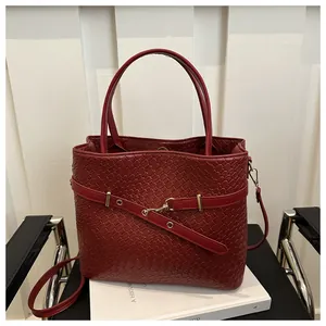 Dettaglio ravvicinato della borsa a secchiello intrecciata rossa con finiture dorate