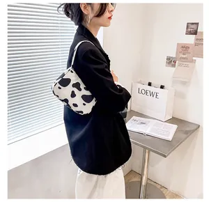 Detail of a black and white cow print baguette bag styled with a black blazer jacket