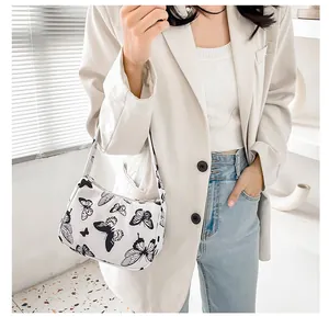 Close-up of white shoulder bag featuring black butterfly print on textured fabric material