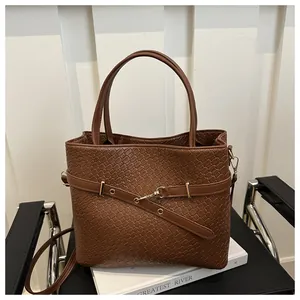 Dettaglio della trama in pelle intrecciata di una borsa a secchiello marrone con fibbia