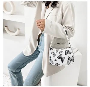 Detailed view of white shoulder bag with black butterfly print worn by a model