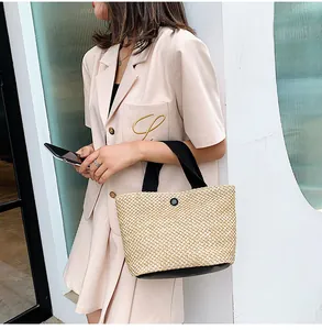 Detail of straw handbag with black contrast trim held by model in casual chic outfit
