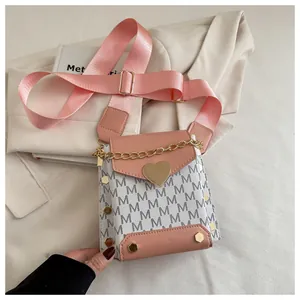 Detail of a pink square crossbody bag with M-pattern canvas and a heart metal buckle