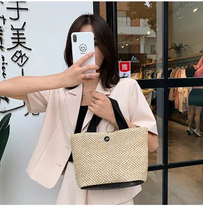 Mirror selfie showing a beige straw tote bag with black handles in a lifestyle setting