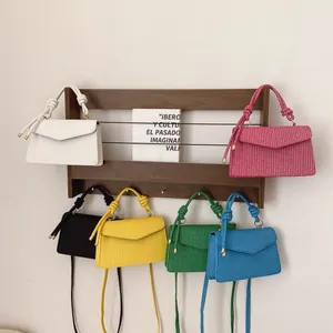 Sacs à main carrés tissés en six couleurs vives disposés sur une étagère en bois