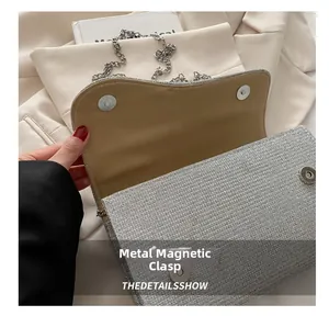 Detail of silver glitter handbag featuring a magnetic hardware buckle and metal chain strap