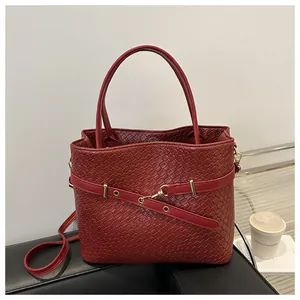 Dettaglio borsa a secchiello rossa intrecciata con fibbia dorata e tracolla regolabile