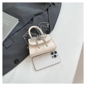 Chic cream mini square bag with crystal bow detail and silver chain strap