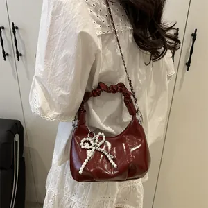 Sac bandoulière chic en cuir verni bordeaux avec nœud perlé et chaîne tressée