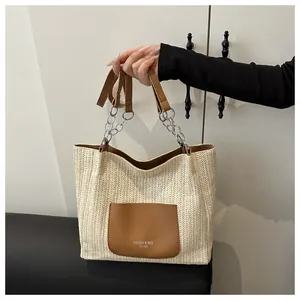 Detail of herringbone straw tote with brown leather pocket and metallic chain strap