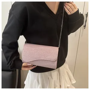 Close-up of pale pink glitter evening bag with silver chain strap shown worn by person