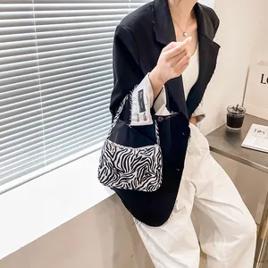 Fashionable black and white zebra pattern shoulder bag held by a model in casual blazer