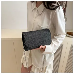 Detail of black sequined evening clutch with elegant silver chain strap and flap closure