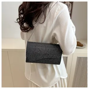 Detail of elegant black sequin evening bag with silver metal chain on a white garment