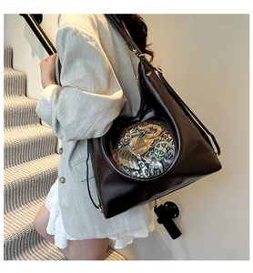 Detail of dark brown tote bag featuring a vintage elephant embossed metal ornament