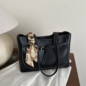Minimalist black tote bag with white contrast stitching and elegant silk scarf accessory