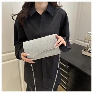 Detail of silver sequin clutch bag featuring shiny texture and a slim metal chain strap