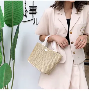 Detail of a beige woven straw handbag with a white circular buckle and fabric handles