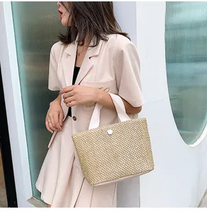 Detailed view of woven straw tote bag featuring cotton handles and a round button closure