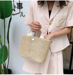 Detailed view of handmade straw tote bag with woven texture and white fabric handles