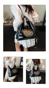 Detail of black leather hobo bag featuring ethnic elephant embossed pattern and gold buckle